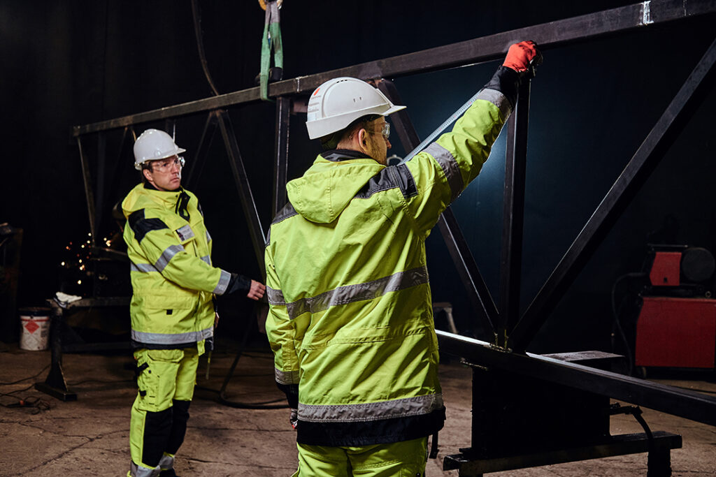 Warehouse workers are check in measurements of rail at metal factory.